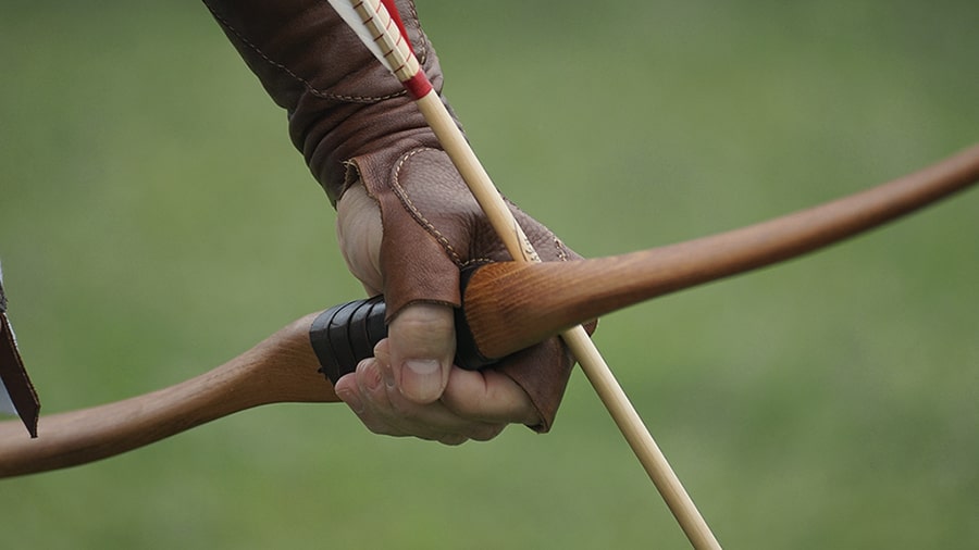 Image of a gloved hand gripping a bow and arrow.