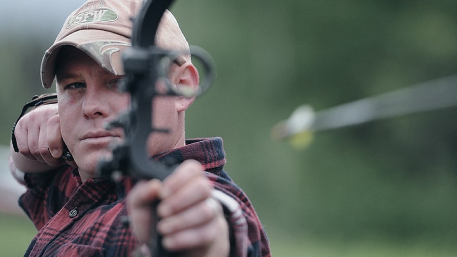 Image of a man looking down the sight of his bow just after releasing an arrow.