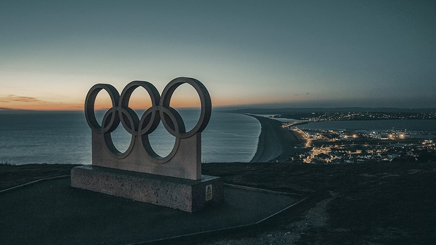 Image of a Olympics symbol statue on a cliff overlooking the ocean.